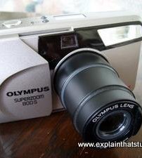 An Olympus 35mm film camera with telefoto zoom lens.